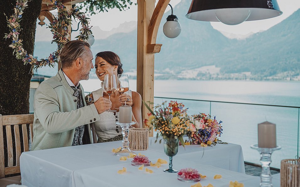 Ein Paar sitzt an einem gedeckten Tisch auf einer Seeterrasse.