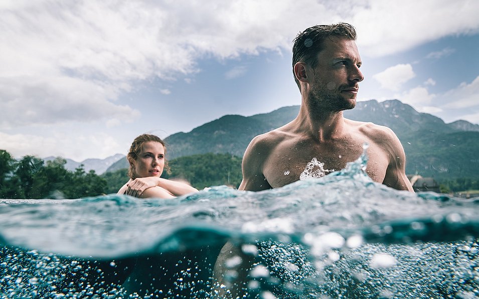 Ein Paar im Infinity Pool im Wellnessbereich SkyLounge auf dem Dach des Hotel Royal im EurothermenResort Bad Ischl im Salzkammergut, im Hintergrund das Panorama der Berge rund um Bad Ischl.